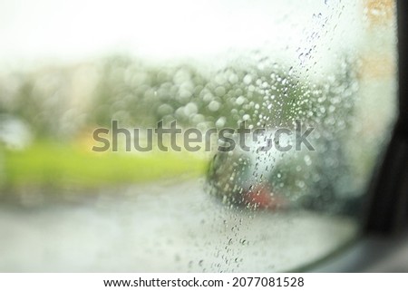 Autumn. Raindrops slowly trickle down the glass of the car behind which a wet city can be seen