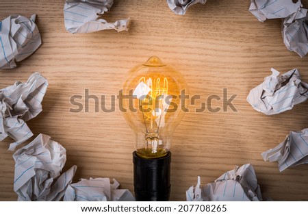 Light bulb with Crumpled paper on wood background