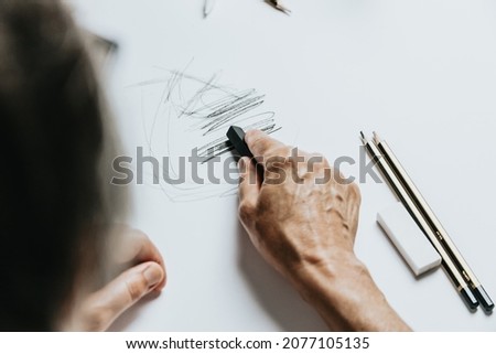 High angle view of a senior Caucasian woman drawing sketches in studio. Creativity, education and people concept,cognitive functions clock drawing self assessment test at home with positive results