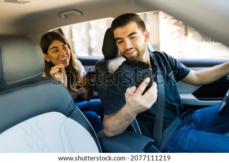 Hispanic driver on a rideshare app. Handsome man driving a young woman passenger to her destination  Royalty-Free Stock Photo #2077111219