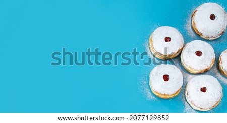 Symbols of Jewish religious holiday Hanukkah. Traditional dessert donuts sufganiyot on blue background. Copy space, banner format