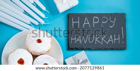 Happy Hanukkah. Jewish dessert sufganiyot donuts on blue background. Symbol of religious Judaism holiday. Inscription on the chalk board.