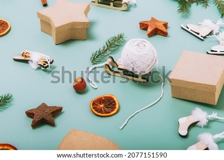 Christmas side view green background with fir branches, eco friendly cardboard gift boxes, wooden toys, cinnamon, dried oranges and rope for gift packaging. Zero-waste, no plastic holidays.