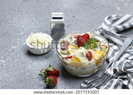 landscape picture of colourfull creamy fruit salad served in bowl with gray background