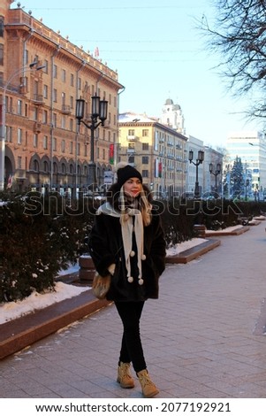 One of the central streets of the city of Minsk with a woman in winter clothes with a warm hat and black fur coat.