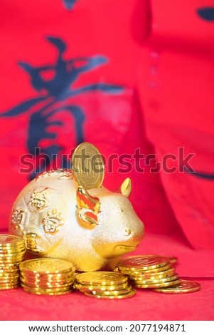 Gold coins and a golden calf piggy bank on a red background. The Chinese characters in the picture mean "peace and wealth"