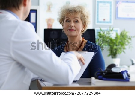 Senior woman on appointment in hospital listen to doctors prescription