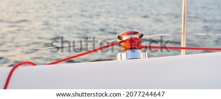 White yacht sailing after the storm. Boat side railing, mast winch, red rope close-up. 32 feet swedish built cruising sailboat. Mälaren lake, Sweden. Cruise, recreation, sport, leisure activity Royalty-Free Stock Photo #2077244647
