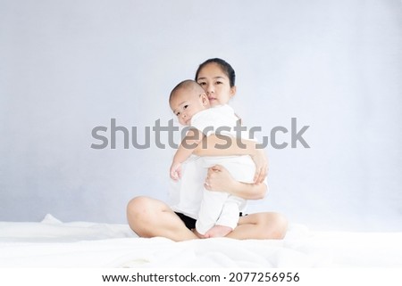 Mother and baby at home on a white mattress bed