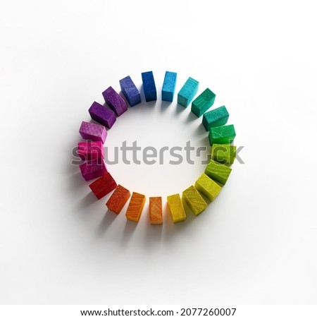 Color wheel of wooden blocks. Colors of unity. Circle of colored blocks representing unity of diverse elements. Wooden blocks placed in a a circle on a neutral white background, with natural shadows.  Royalty-Free Stock Photo #2077260007
