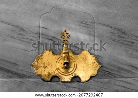 Ottoman style golden-colored antique ablution tap on marble background. Royalty-Free Stock Photo #2077292407