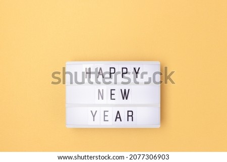 Happy New Year. White lightbox with phrase on a golden background with copy space.