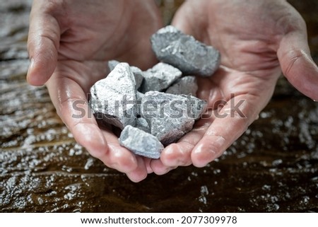 Miners hold in their hands platinum or silver or rare earth minerals found in the mine for inspection and consideration Royalty-Free Stock Photo #2077309978