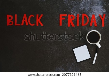 Black Friday concept. Inscription "black friday", coffee cup, pen, notebook on black background. Copy space, top view, flat lay. Creative holiday flyer. Sale. 