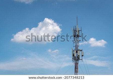 Telecommunication tower and its wireless cellular transmission antenna in blue sky and white cloud background. Mobile phone network transmitter technology and telephone communication concept. Royalty-Free Stock Photo #2077348213