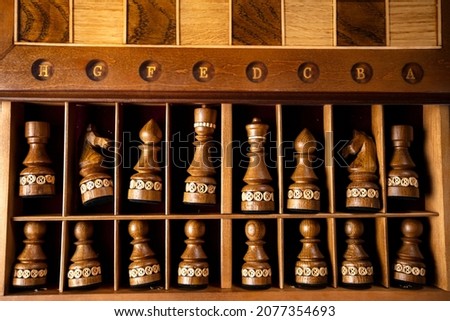 Dark chess pieces lie in a box. A puzzle game with tricky combinations that requires planning and thinking.