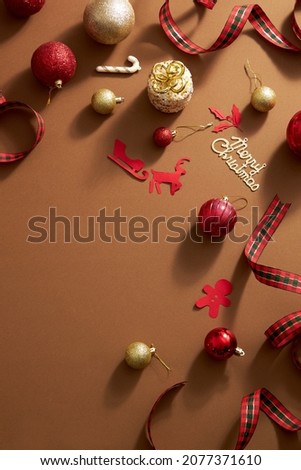 Brown background with colorful christmas ornament decoration , red gift box and ribbon with candy for holiday , top view with blank space for holiday advertising