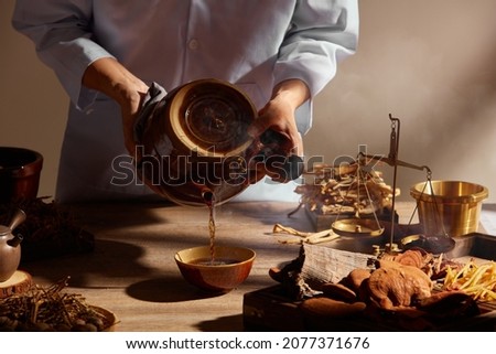 Traditional chinese medicine with herb and spices in brown wooden background doctor using a traditional kettle for advertising , chinese traditional content  Royalty-Free Stock Photo #2077371676