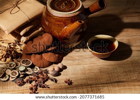 Traditional chinese medicine with herb and spices in brown wooden background and traditional kettle with medicine bowl , for medicine advertising , photography traditional medicine content