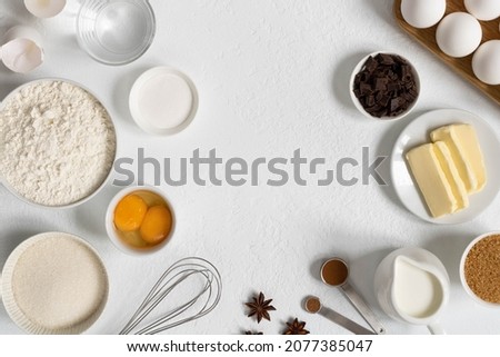 Frame made of ingredients for baking. Ingredients for making dough, cakes, muffins, bread. Baking ingredients: flour, sugar, eggs, spices, milk, chocolate, baking powder Royalty-Free Stock Photo #2077385047