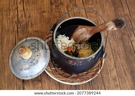 Indonesian traditional food named "nasi liwet" i.e. cooked rice mixed with santan added by some crispy anchovies, cooked and served in a vintage pot