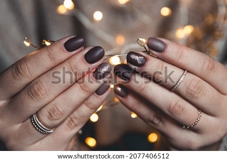 manicure nail art design for new year, christmas cat eye effect black purple golden chameleon shining sparkling on the background of the Christmas tree