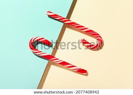 Two candy canes on color background
