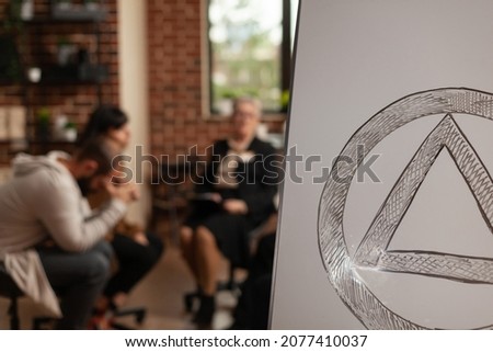 Close up of aa therapy meeting symbol on white board. People having sign and attending support group session with psychiatrist. Concept of community rehabilitation program with patients. Royalty-Free Stock Photo #2077410037