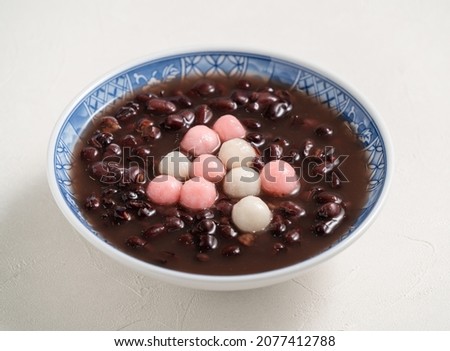 Close up of red and white tangyuan (tang yuan, glutinous rice dumpling balls) with sweet red bean soup in a bowl on white table background for Winter solstice festival food. Royalty-Free Stock Photo #2077412788