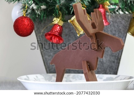 Christmas seasonal pic, Chocolate reindeer on a plate facing right, in front of a small Christmas tree