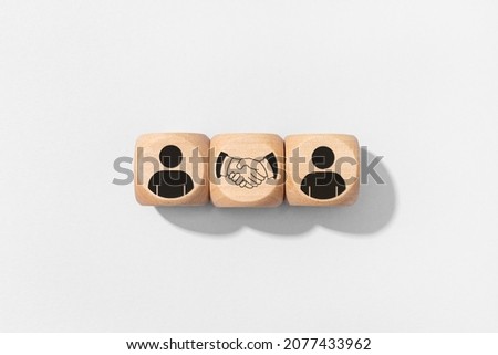 Agreement, partnership or deal concept. People and handshake Icons on wooden blocks isolated on gray background