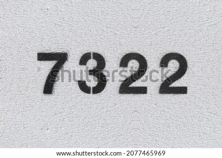Black Number 7322 on the white wall. Spray paint. Number seven thousand three hundred and twenty two.