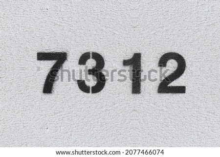Black Number 7312 on the white wall. Spray paint. Number seven thousand three hundred and twelve.