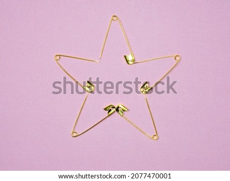 gold pins on pink background, star of pins, open pins are laid out in the shape of a five-pointed star Royalty-Free Stock Photo #2077470001