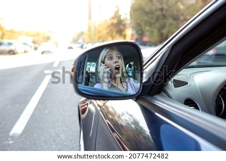 Shocked face in the side view mirror, unsafe reckless driving Royalty-Free Stock Photo #2077472482