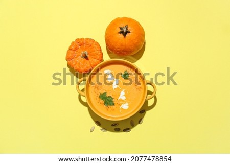 Pot with delicious pumpkin cream soup on color background