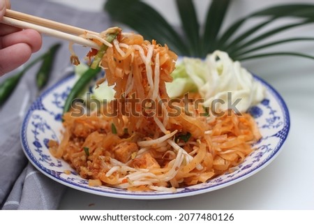 Thai food Pad Thai (national dish) served in a Chinese-style patterned bowl. Place it on a white table.
