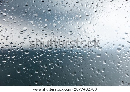 raindrops on the glass and a cloudy landscape in the background