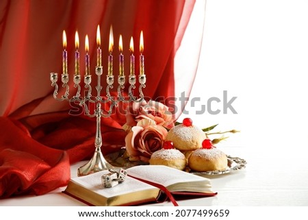 Day 7 of Jewish religious holiday Hanukkah with holiday Hanukkah (traditional candelabra), spinning top toys (dreidels), doughnuts, and Tanakh
