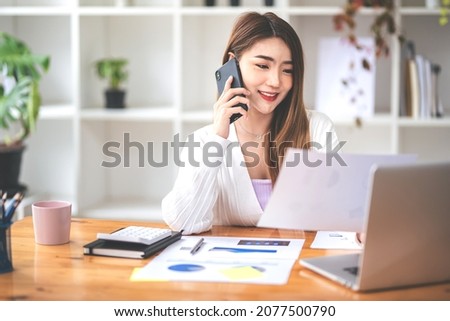 Businesswoman or accountant using the phone to check business information. Accounting Documents and Laptop Computer at Office Business Ideas