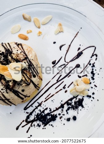 Top view of bright white donut on white round plate .Isolated object close up. Traditional American sweets for breakfast. Copy space. with chocolate decoration on top.