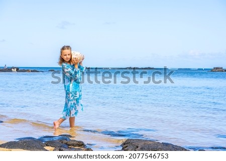 A girl holding and hearing huge big seashell near ear on the summer tropical beach. High quality photo