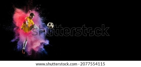 Creative collage of young man, professional football player training isolated over colorful powder explosion on black background. Concept of art, sport, motivation, action. Copy space for ad