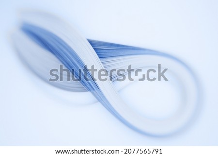 A set of blue quilling strips shot with a creative lens giving selective, shallow depth of field, shaped as an infinity sign with attractive defocussed background bokeh and space for text meta