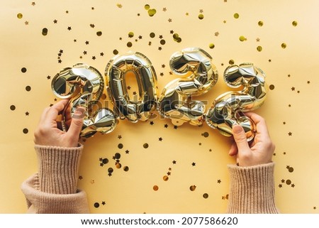 The girl is holding inflatable balloons in the form of New Year's figures in 2022. Festive background of the concept of New Year and Christmas. Flat lay, top view