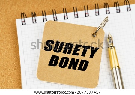 Business and economy concept. There are two notebooks and a pen on the table. On the top notepad, the inscription - SURETY BOND