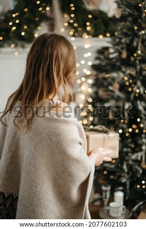 Focus on wrapped Christmas present congratulating with winter holidays, reminding preparing gifts, posing near decorated tree. High quality photo