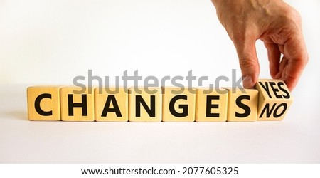 Changes yes or no symbol. Businessman turns a wooden cube and changs words changes no to changes yes. Beautiful white table, white background, copy space. Business and changes yes or no concept.