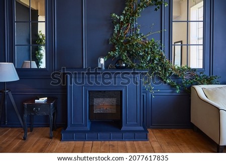 Modern interior with fireplace, spacious living room with blue walls and wooden floors. A real photo of the interior.
