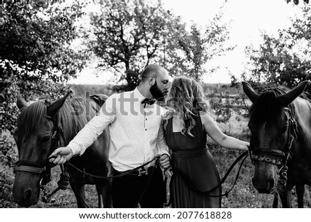 A loving couple on a date. Horseback riding. Purple dress. Black and white photo.